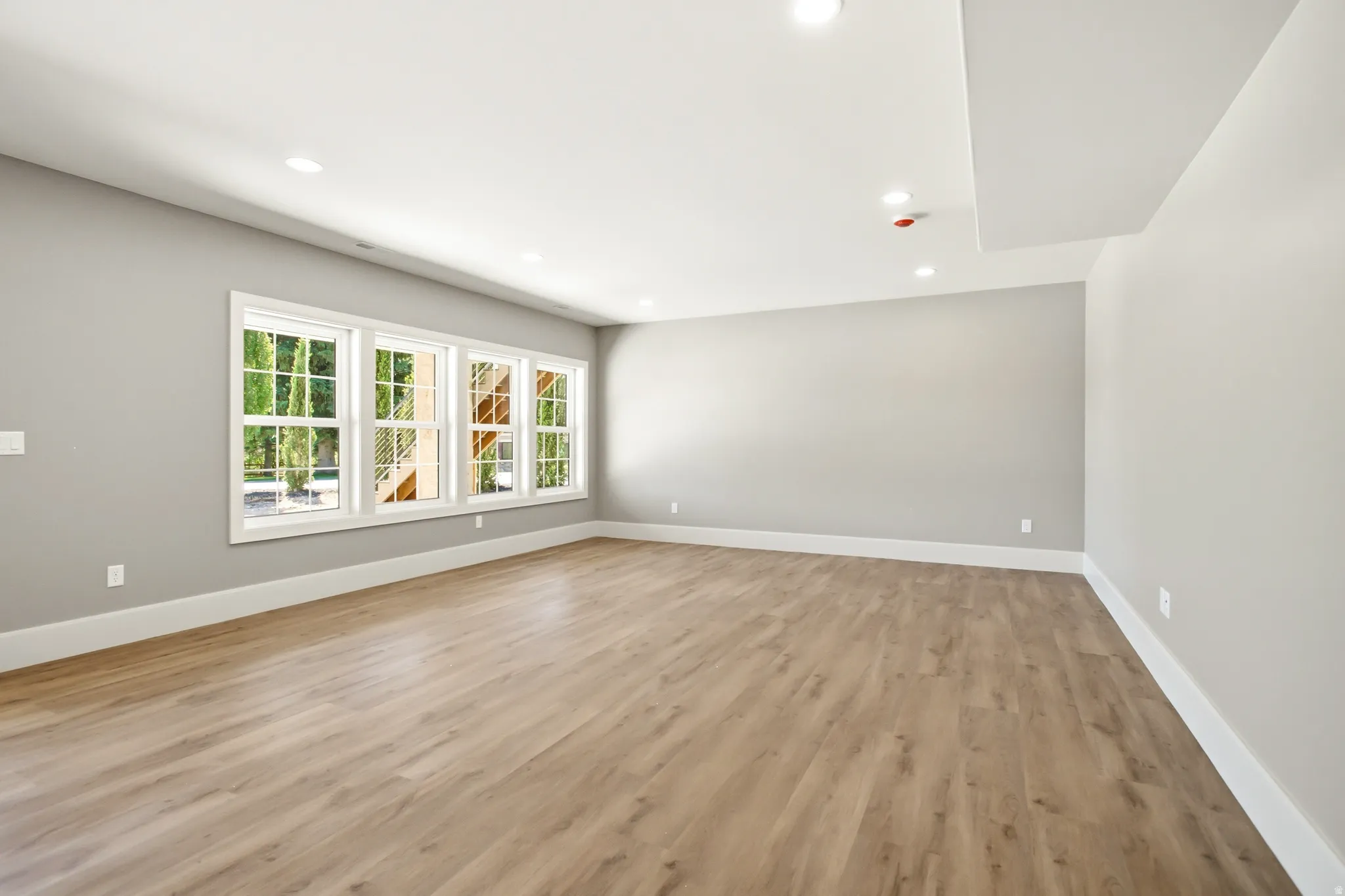 Spacious room featuring light gray walls, and white baseboards