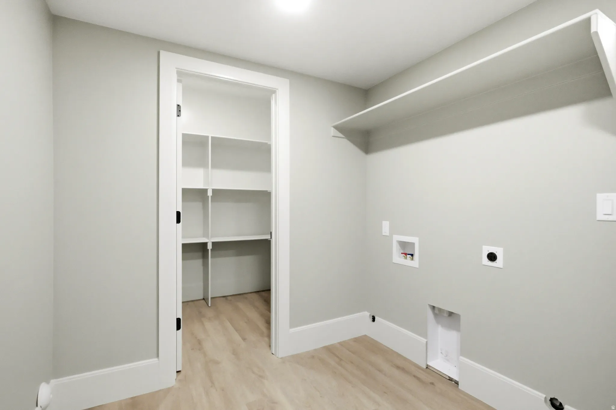 Utility room featuring a built-in shelf, and a pantry with white shelving