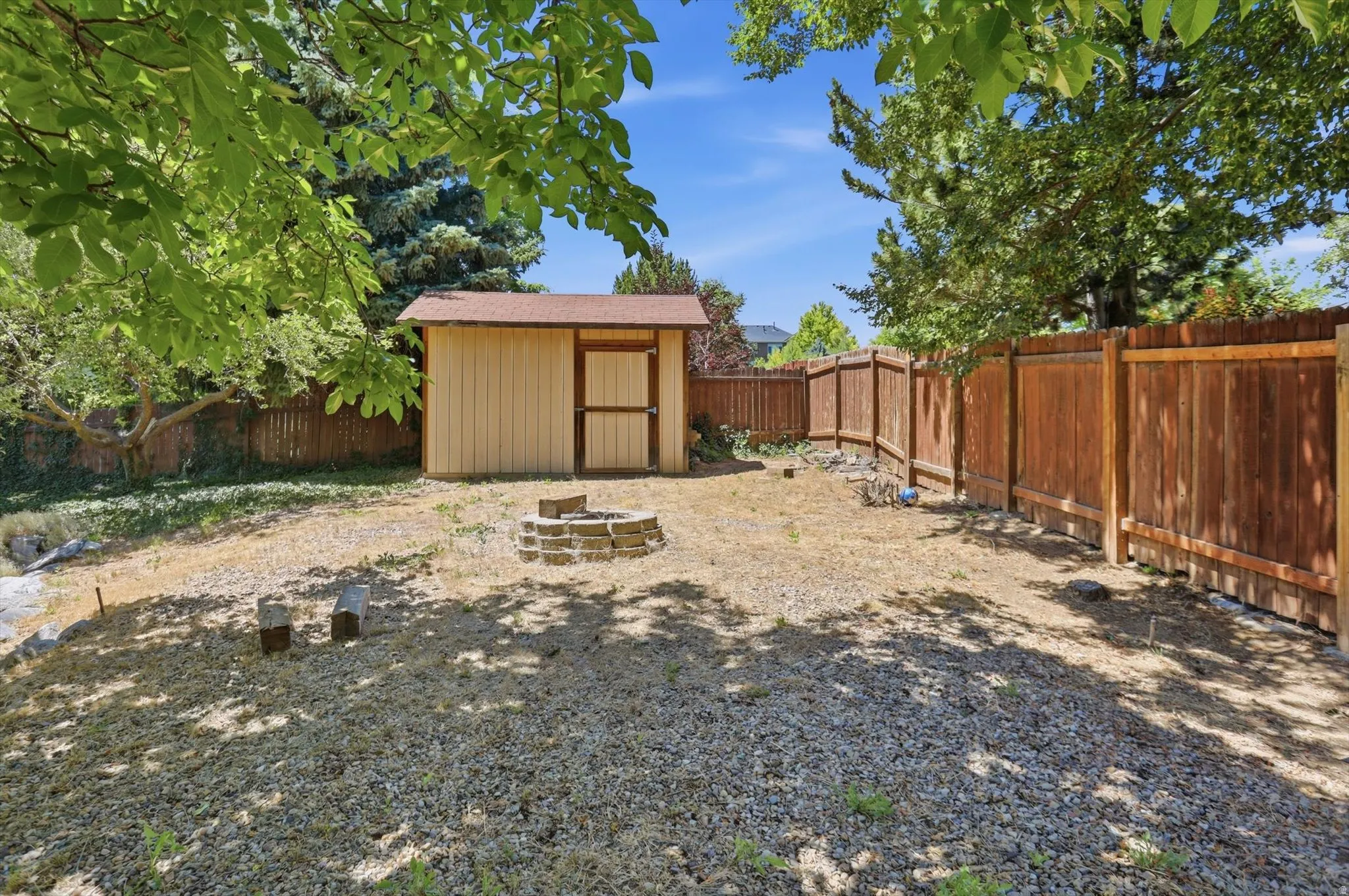 Detached storage shed, wood privacy fencing, and a stone fire pit