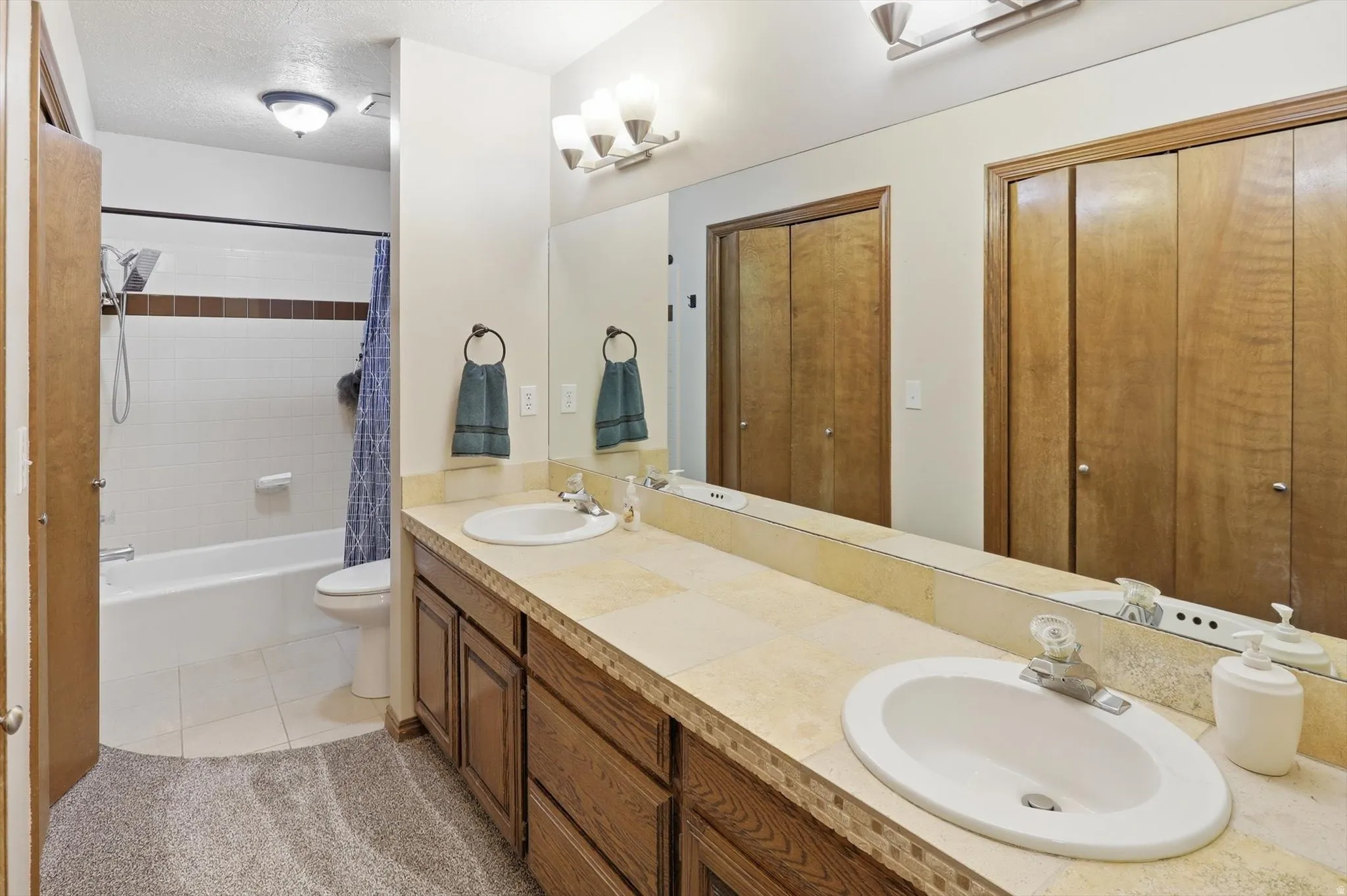 Bathroom featuring a double vanity with integrated sinks and a tile countertop