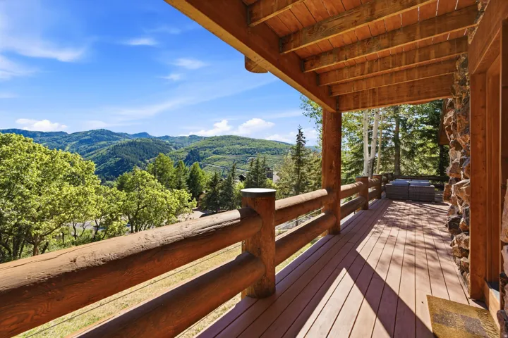 Expansive covered outdoor deck featuring wood plank flooring and log railing