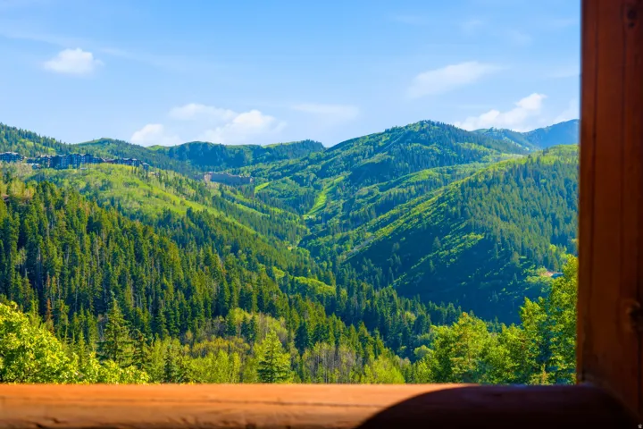 Expansive mountain scenery framed by a rustic wood window