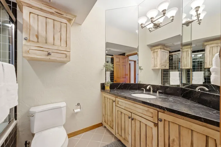 Bathroom featuring a dark stone countertop, an integrated sink, and a rustic wood-finish vanity