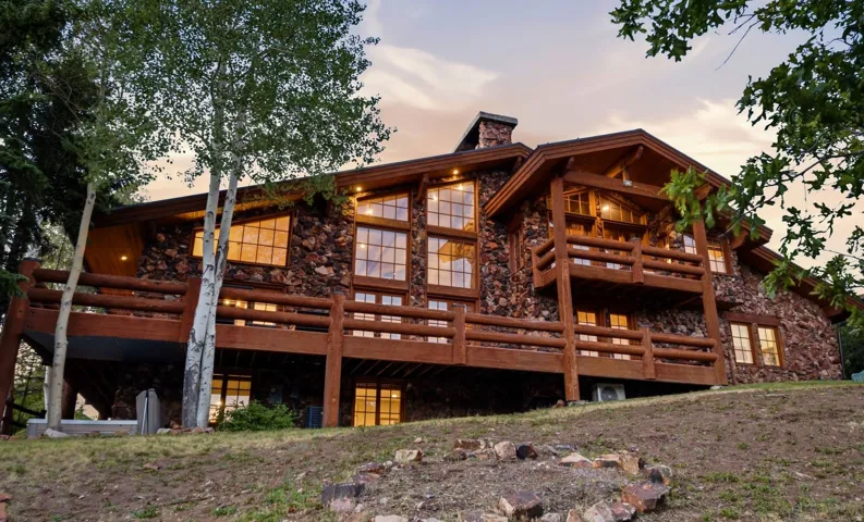 Stone and log exterior architecture featuring multiple balconies and expansive window walls