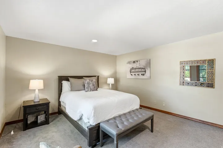 Spacious bedroom featuring neutral wall tones, recessed lighting, and ample natural light