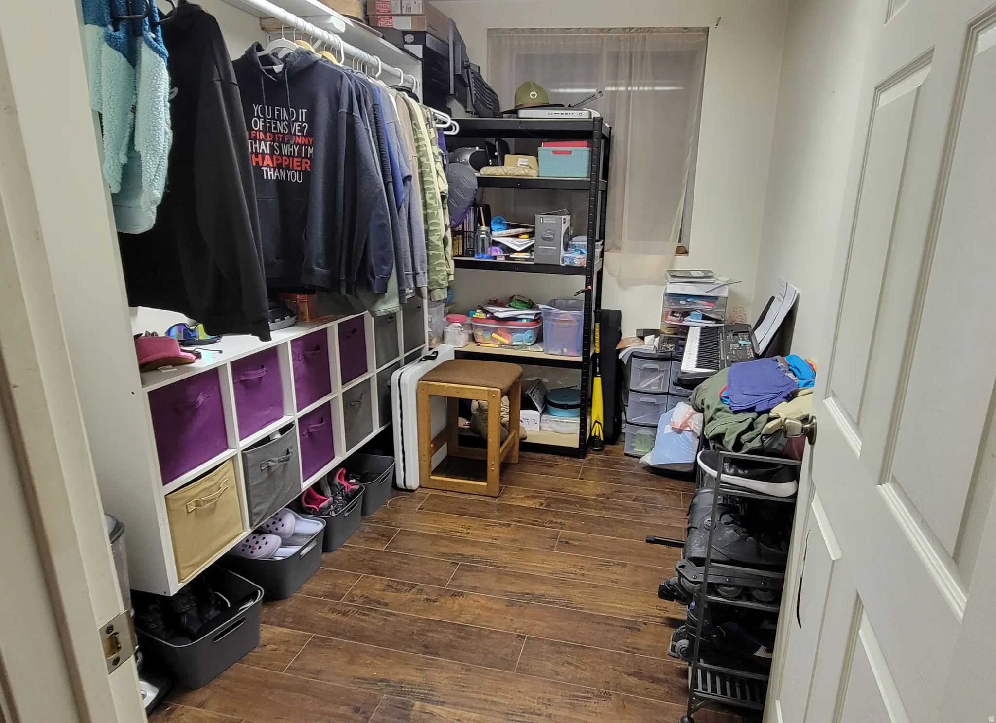 Walk-in closet featuring wood-finish flooring, built-in shelving, and a window for natural light
