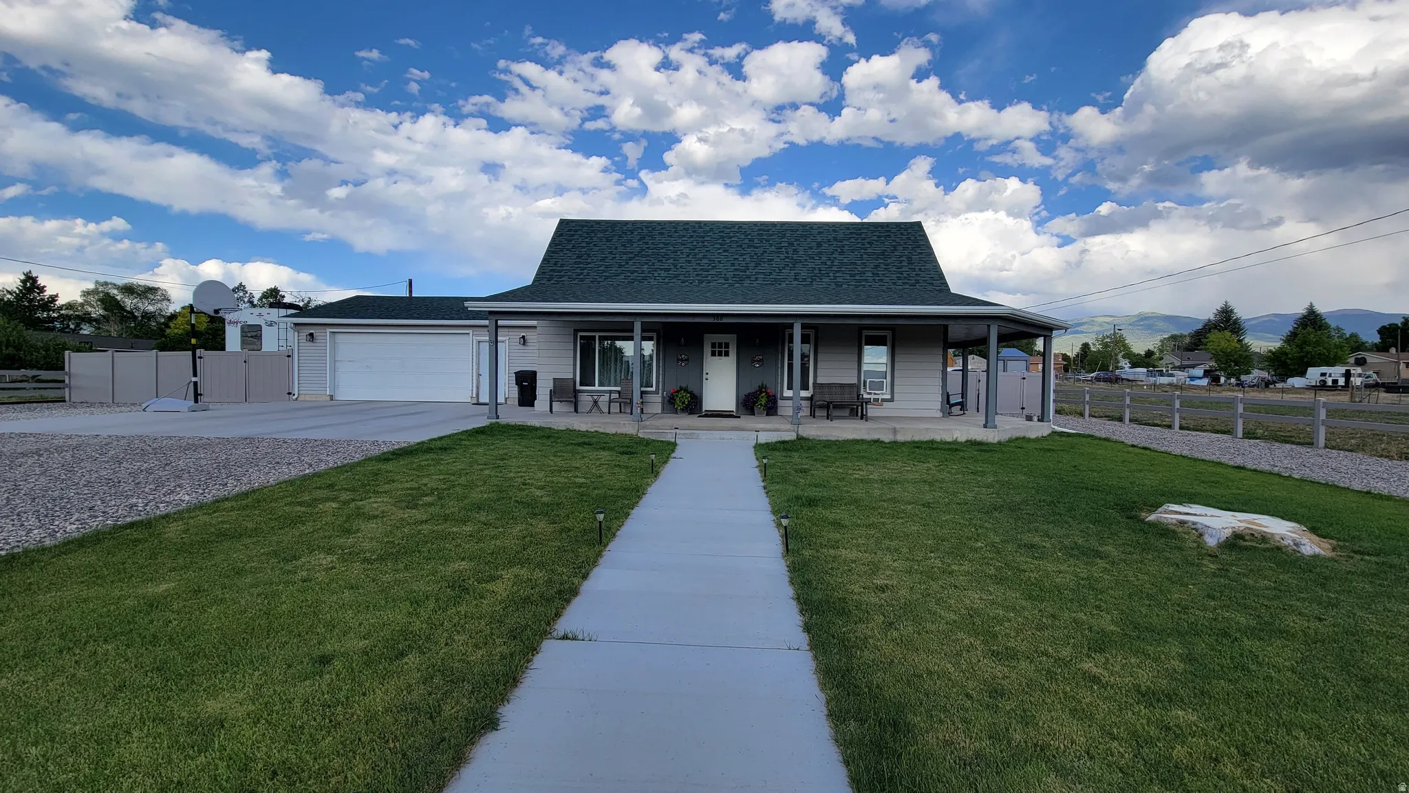 Ranch-style residence featuring a covered front porch, an attached garage, and a long concrete driveway
