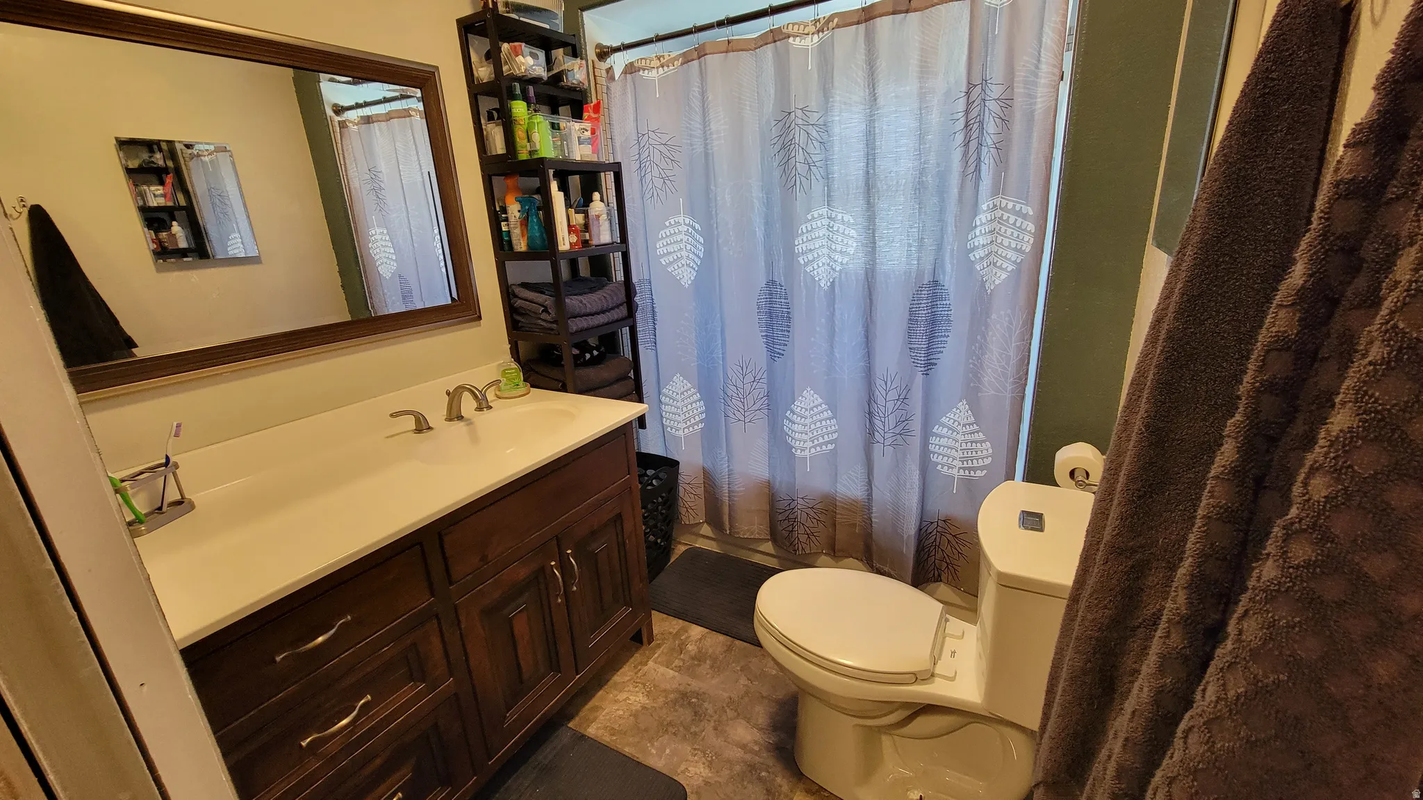 Bathroom featuring a dark wood-finish vanity with an integrated sink and brushed nickel faucet, an overhead framed mirror, a built-in shelving unit, and a white toilet