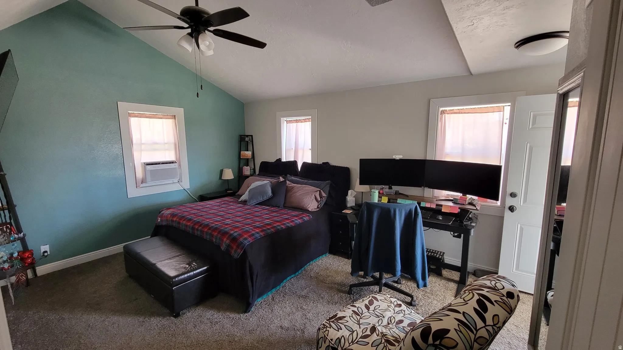 Spacious room featuring vaulted ceilings, a ceiling fan, and multiple windows