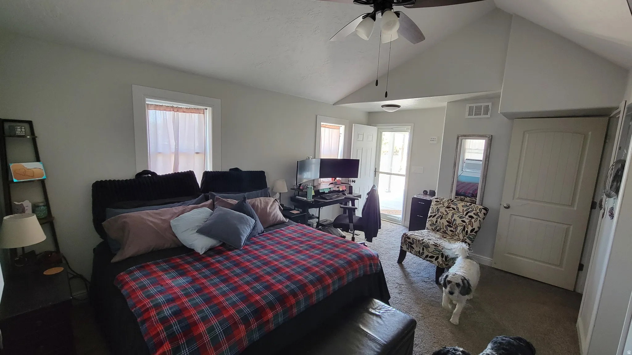 Vaulted ceiling room featuring a ceiling fan with light kit, a window with trim, light-toned wall paint, and carpet flooring