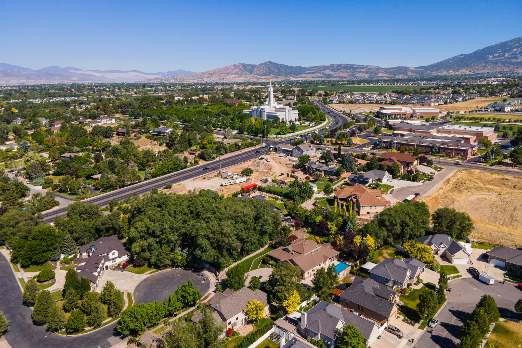 Aerial perspective showcasing a residential area with varied housing styles, mature trees, and mountainous terrain
