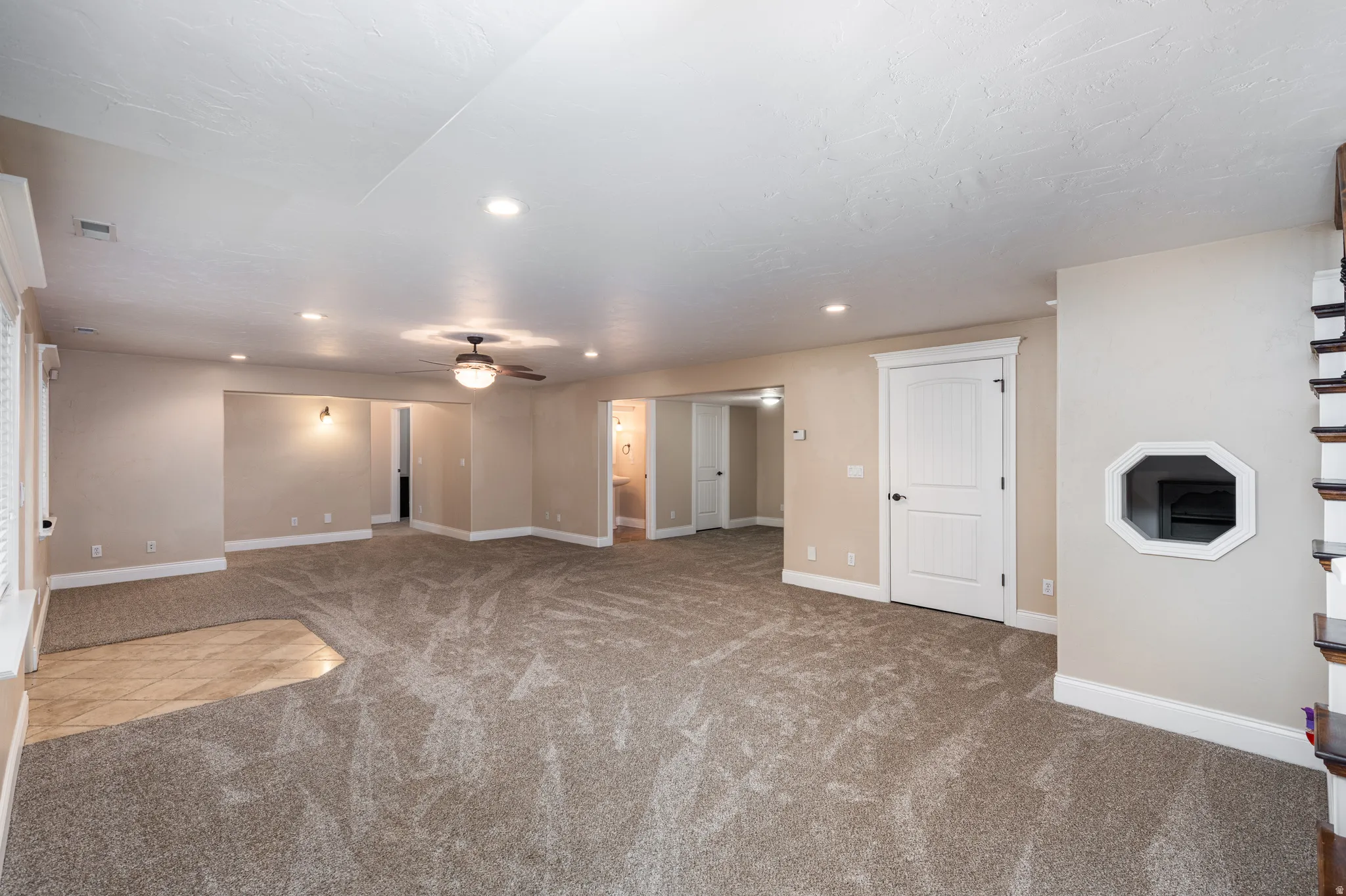 Spacious open-concept room featuring plush carpeting, recessed lighting, and a ceiling fan
