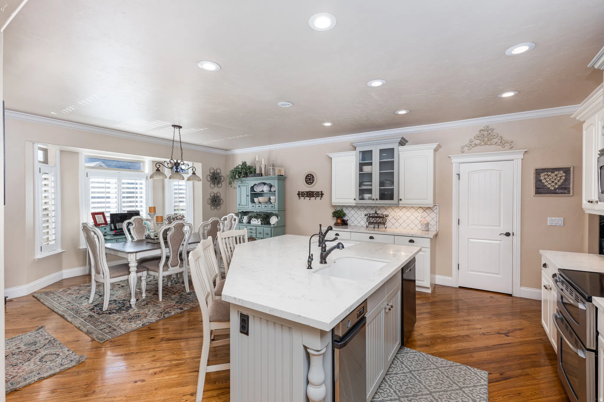 Kitchen featuring a large island with an integrated sink, white cabinetry, and wood-finish flooring