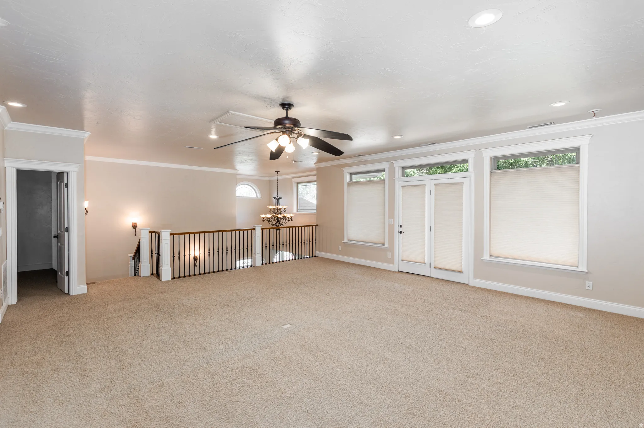 Expansive carpeted room featuring a ceiling fan, recessed lighting, and crown molding