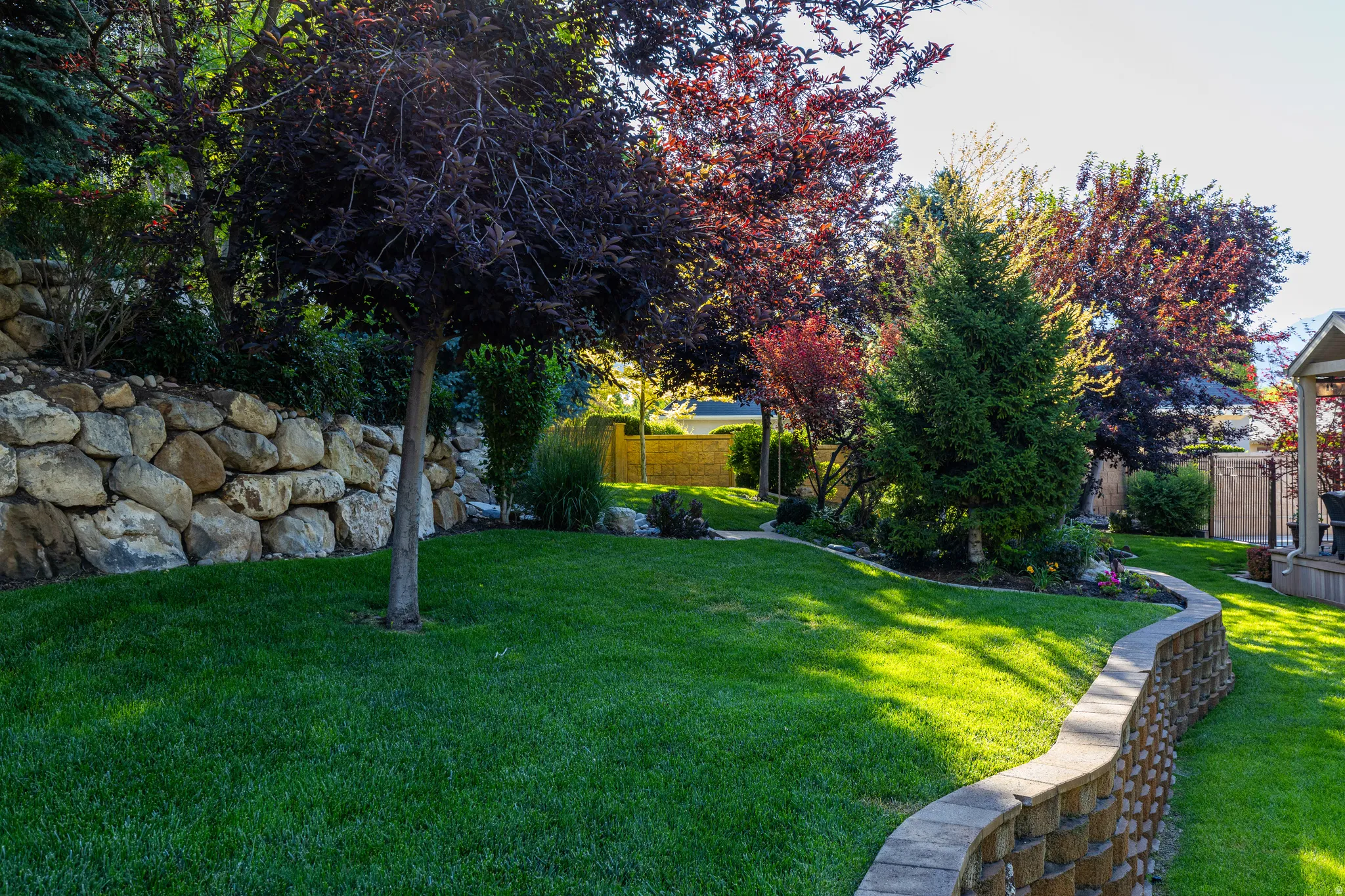 Manicured lawn with a stone retaining wall and mature trees
