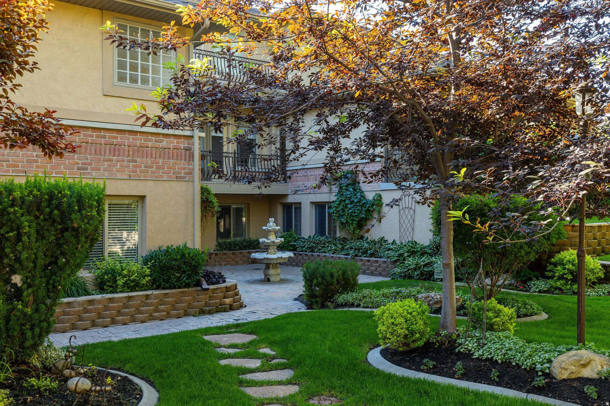 Landscaped courtyard featuring a tiered fountain, paver stone patio, and mature trees
