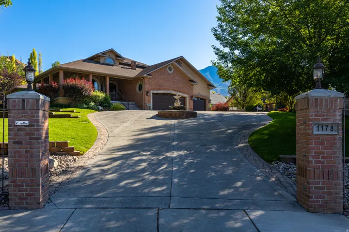 Brick and stone exterior with a concrete driveway, integrated garage, and a fountain feature