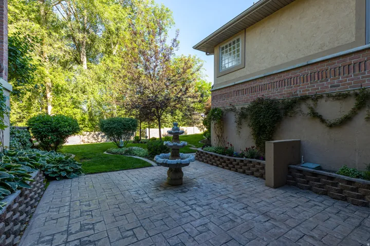 Stamped concrete patio featuring a tiered fountain, bordered by retaining walls with lush plantings