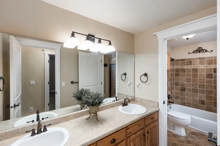Dual vanity with integrated sinks, wood-finish cabinetry, and laminate countertop