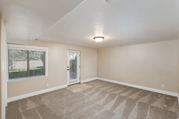 Spacious room featuring patterned carpeting, neutral wall finishes, and white baseboards