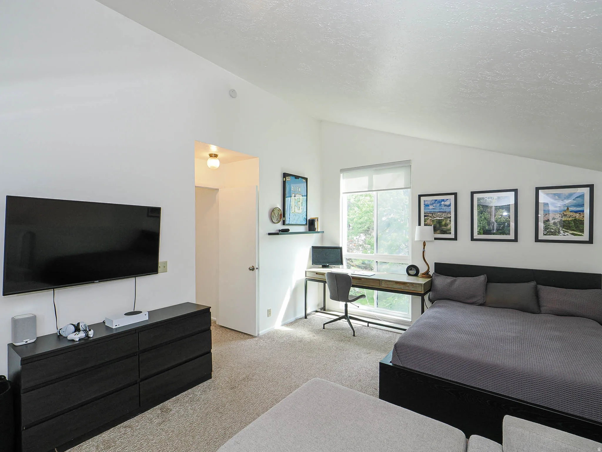 Carpeted room featuring a large window, white walls, and a sloped ceiling