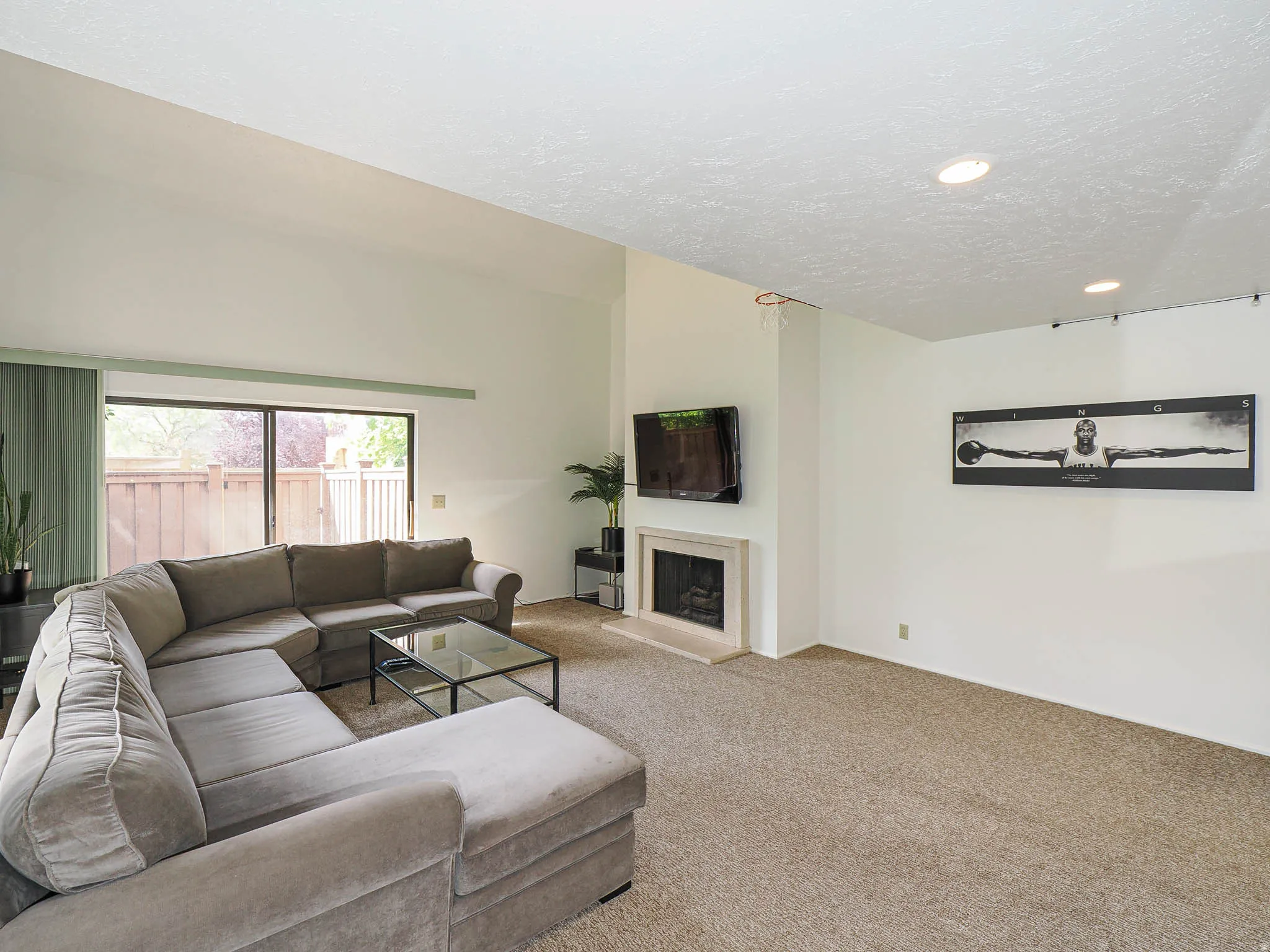 Living area featuring a fireplace with a light-toned surround, a high vaulted ceiling, recessed lighting, and sliding glass doors opening to the exterior