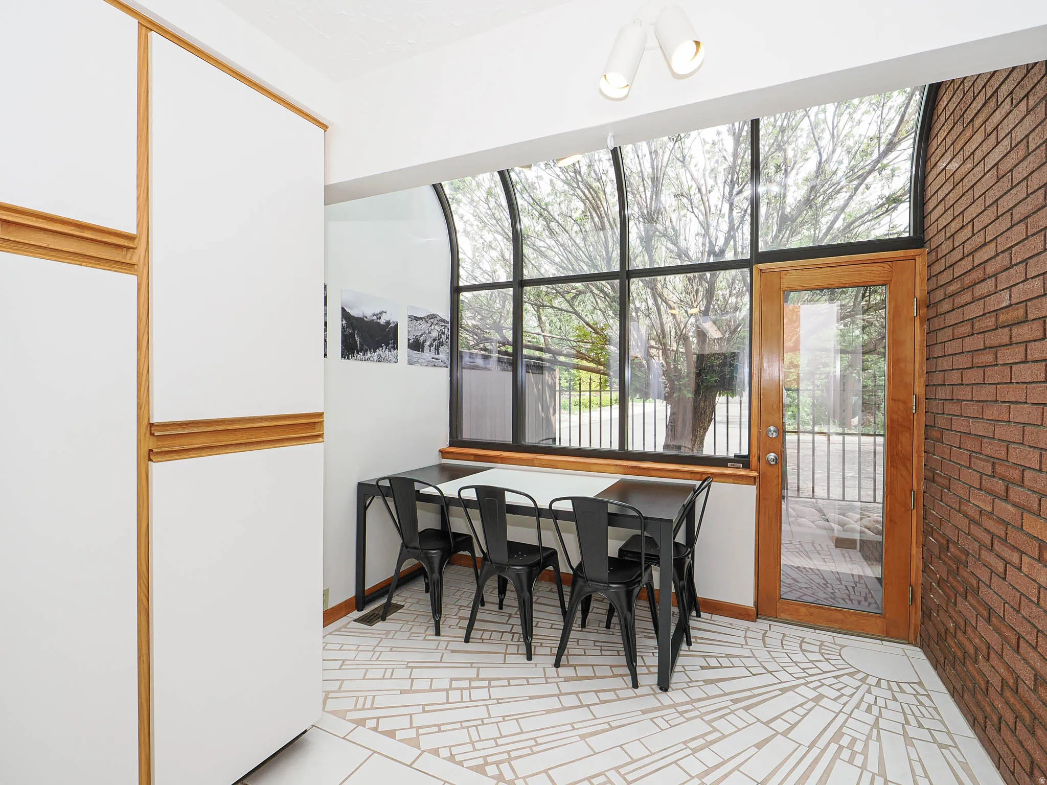 Floor-to-ceiling windows with arched transoms and a wood-frame glass door offer abundant natural light