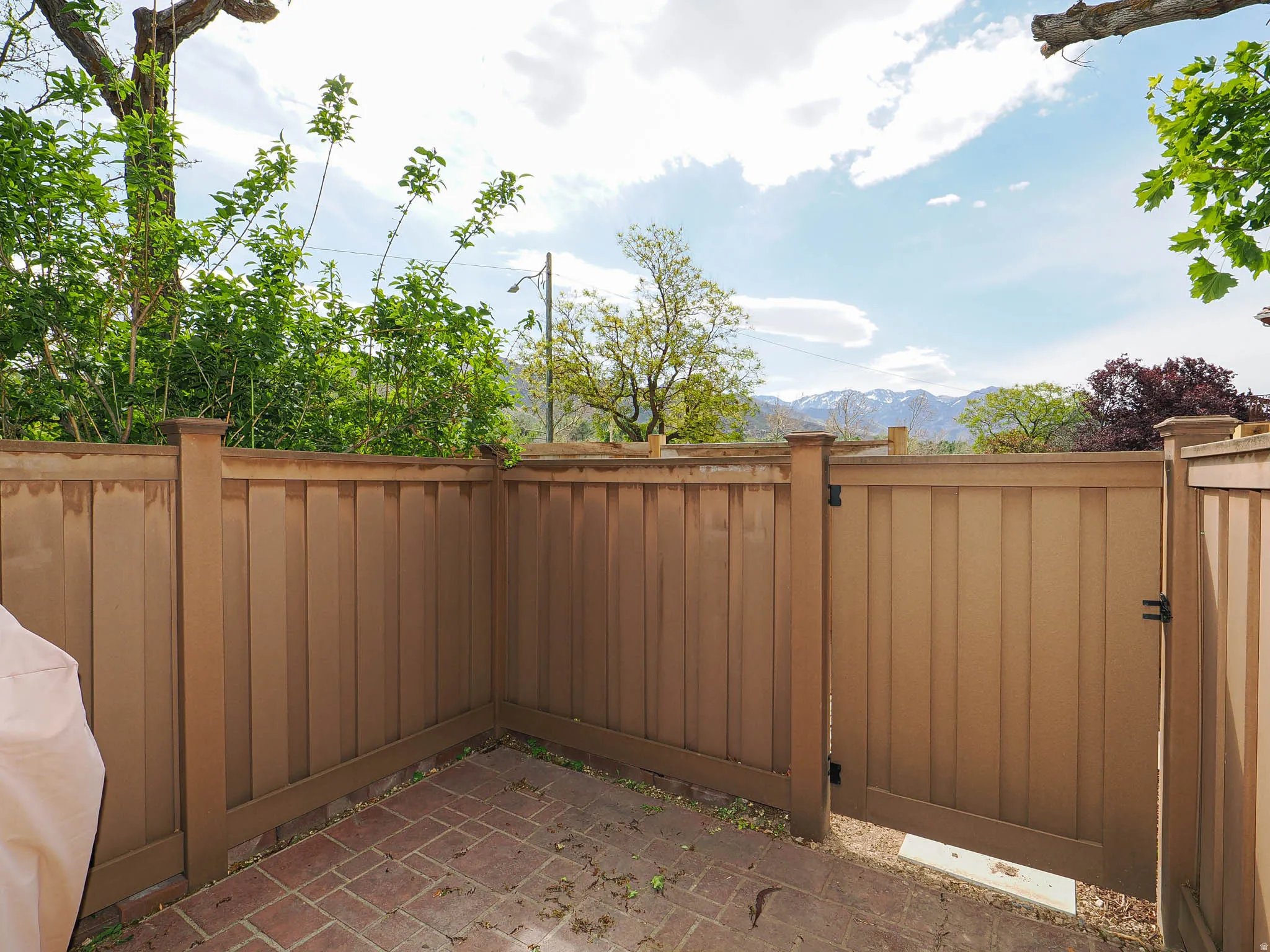 Enclosed patio space featuring brick paver flooring and a private access gate