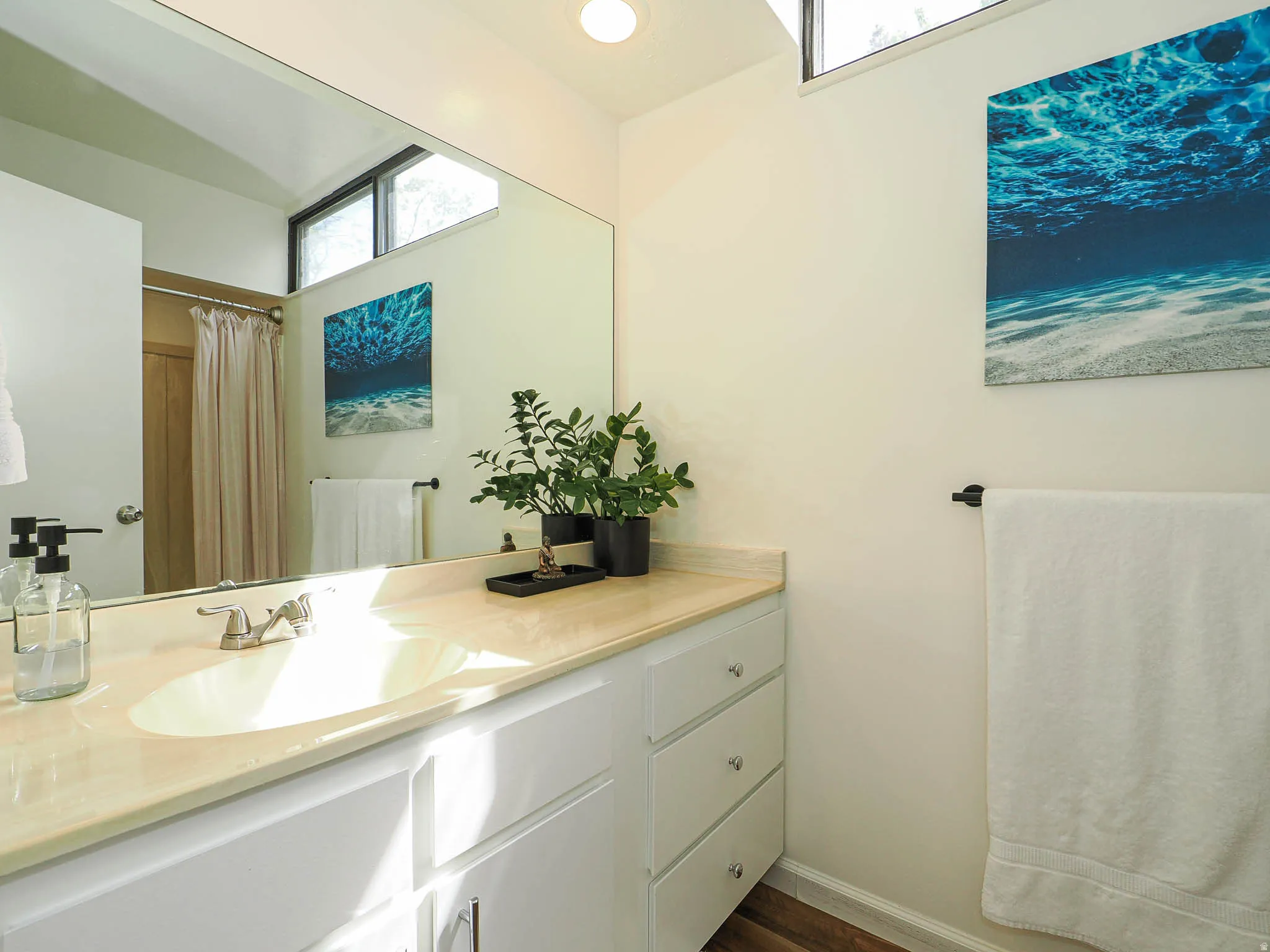 Bathroom vanity with a light-toned countertop, integrated sink, and white cabinetry