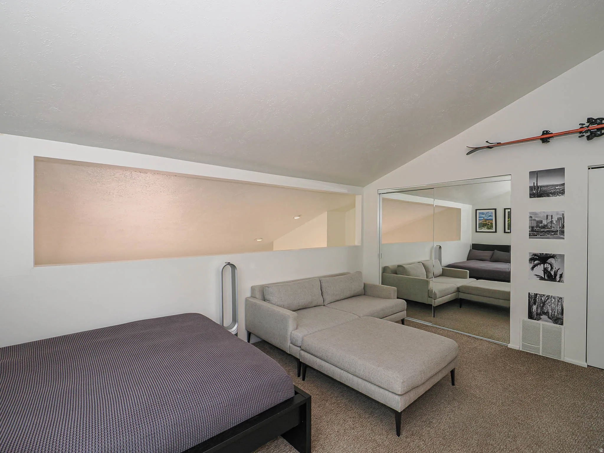 Vaulted ceiling loft space with mirrored closet doors and a built-in wall niche