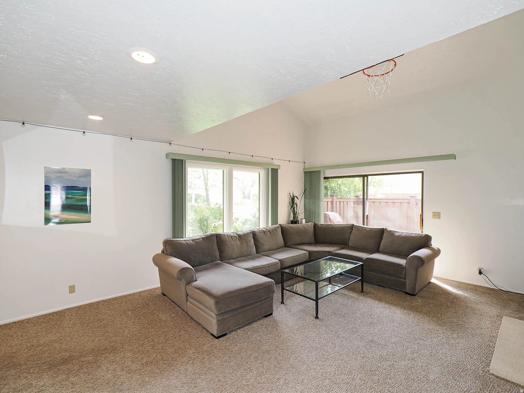 Living area featuring vaulted ceilings, recessed lighting, carpet flooring, a large sliding glass door, and additional windows