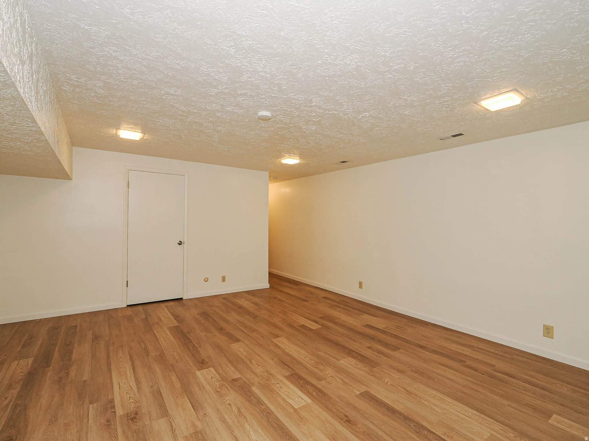 Spacious interior room featuring wood-finish flooring, recessed lighting, and a neutral color palette