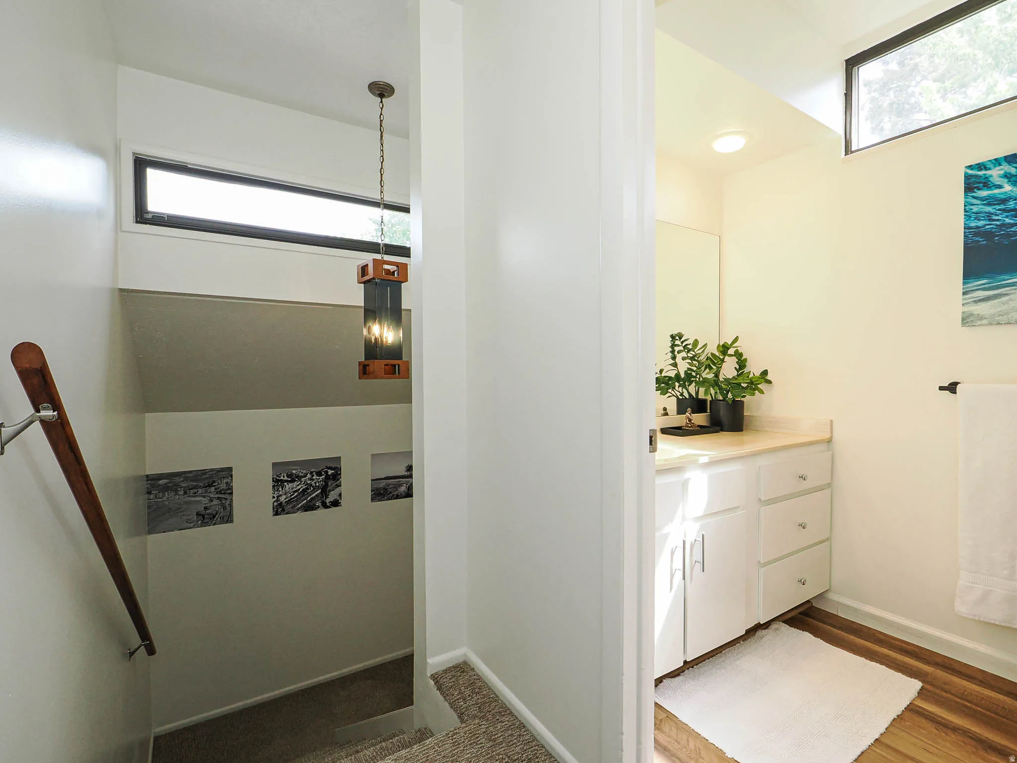 Bathroom vanity with white cabinetry, light-toned countertop, and wood-finish flooring