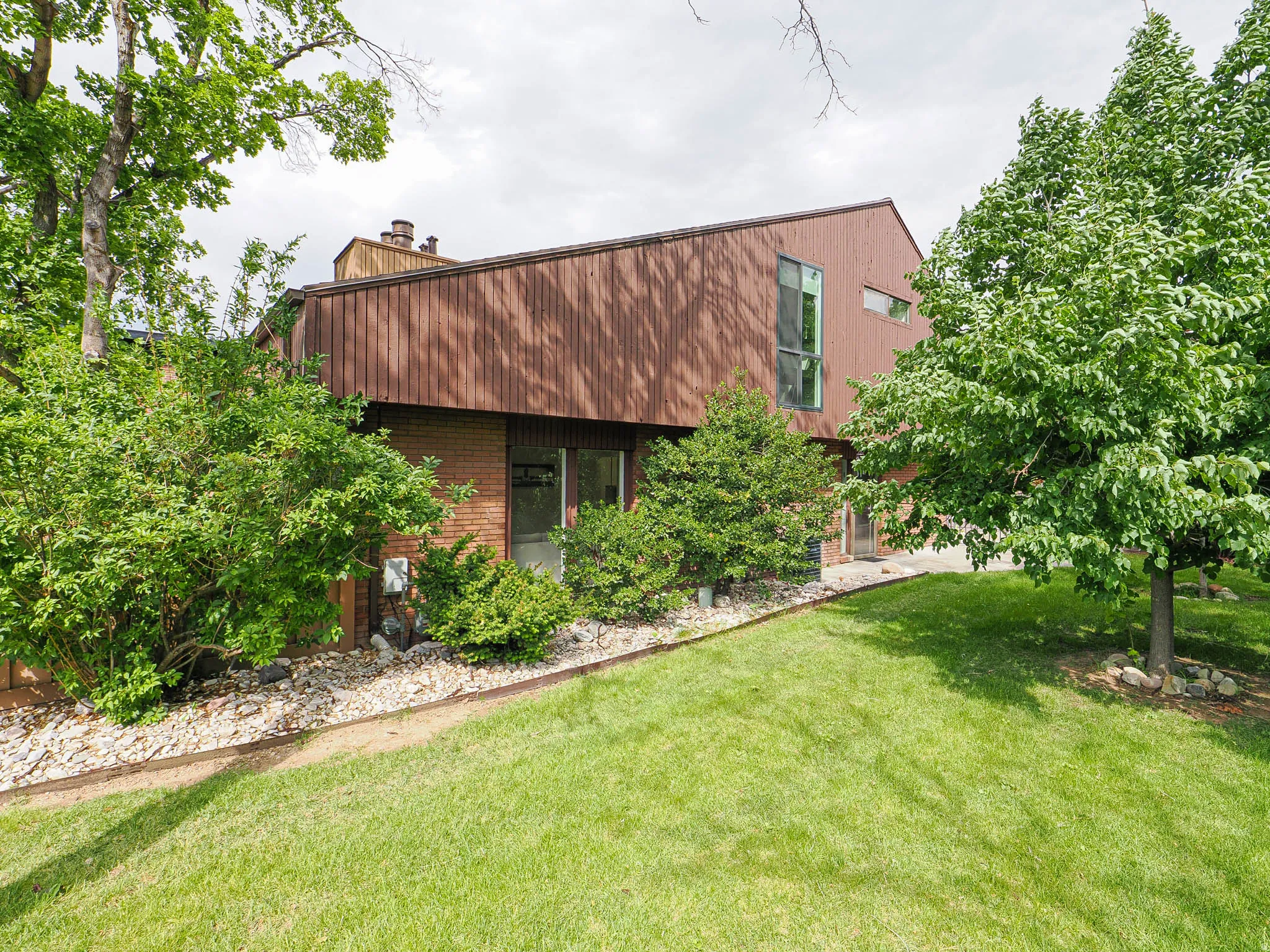Two-story contemporary residence featuring vertical wood-finish siding and brick accents