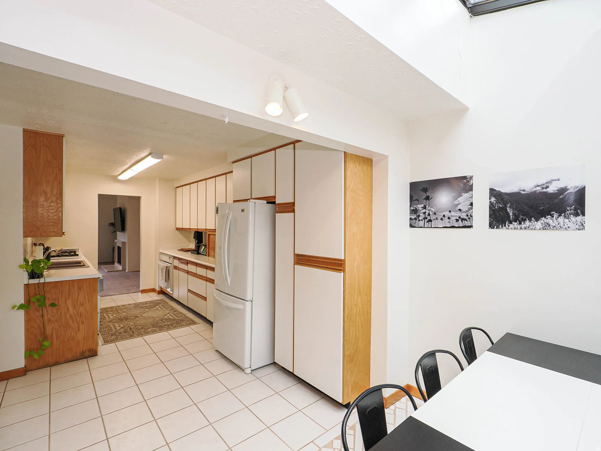 Kitchen area featuring a white tile floor, white appliances, and wood-finish cabinetry