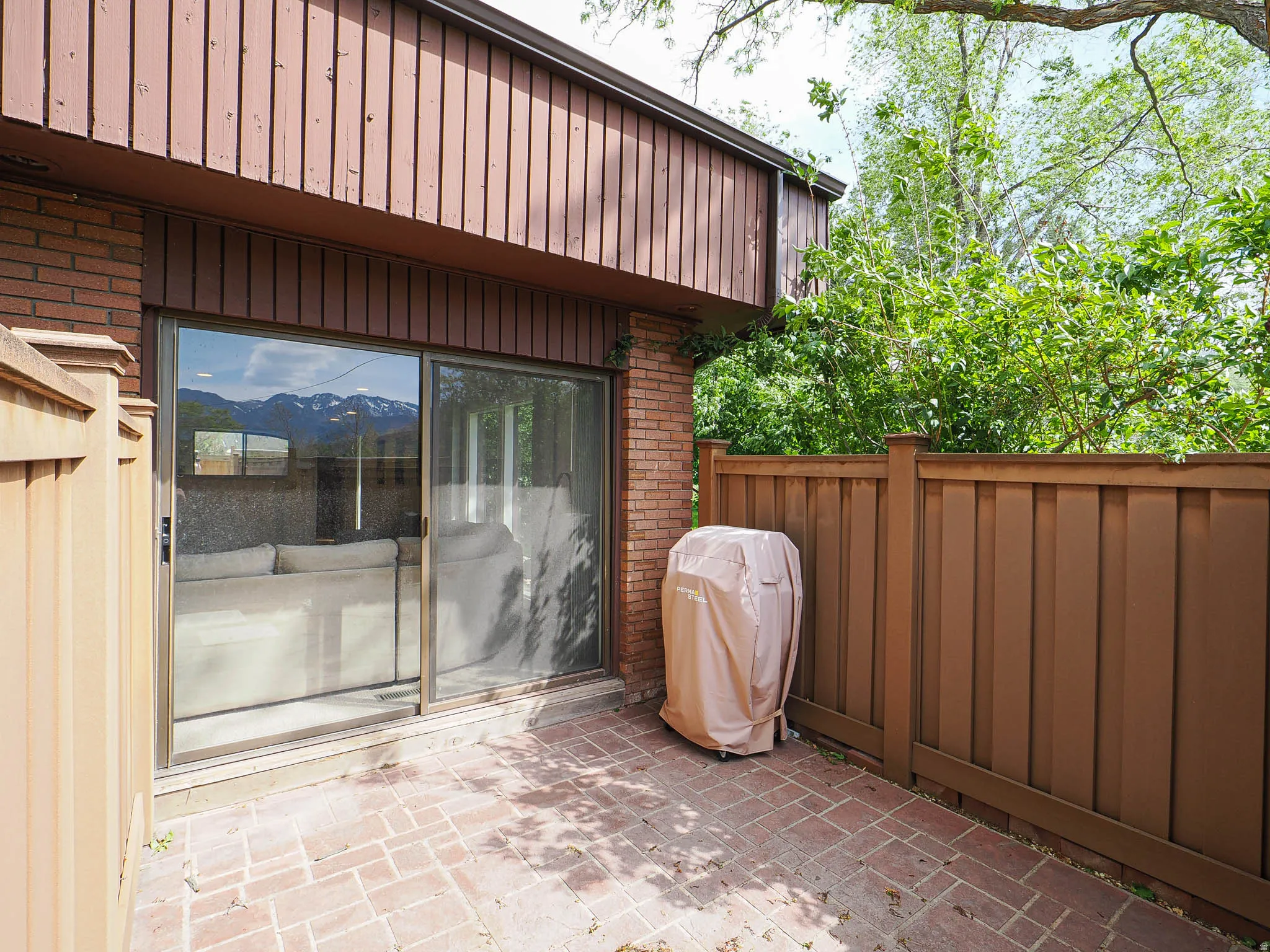 Private patio featuring brick pavers and a full-height wooden privacy fence