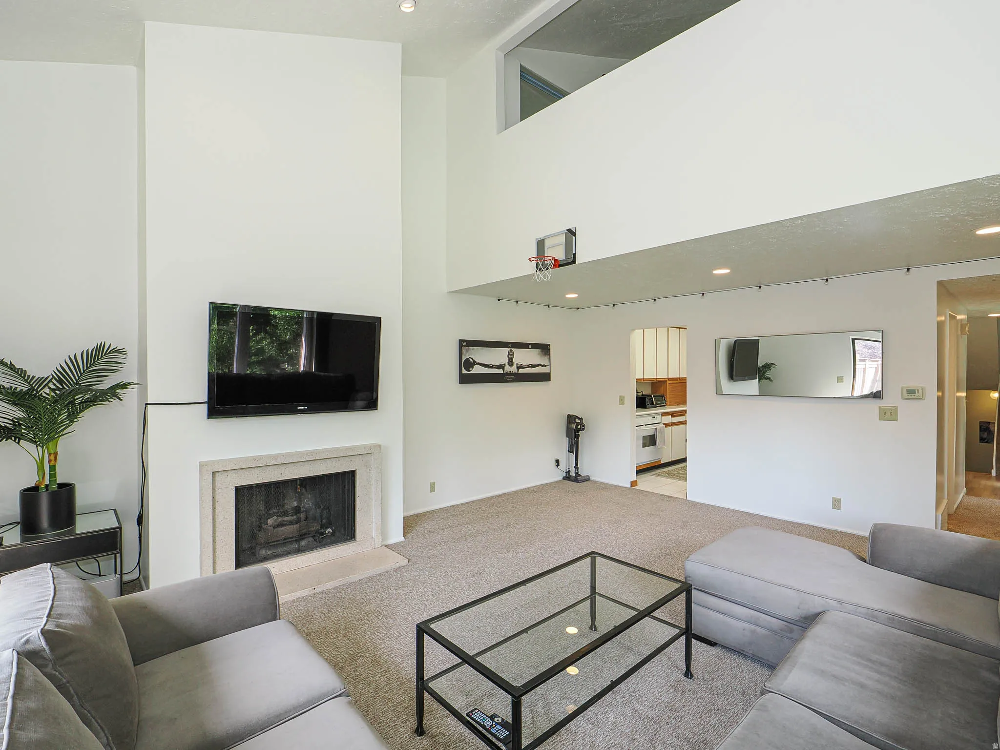 Living area featuring a high ceiling, carpet flooring, and a stone-surround fireplace