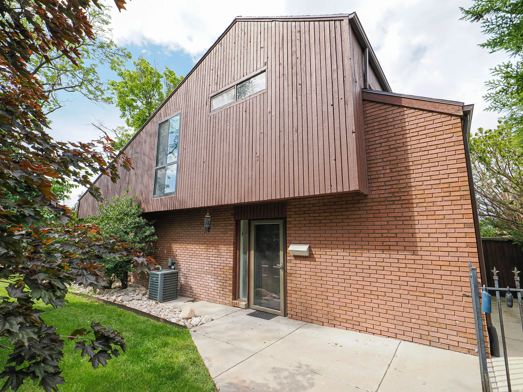 Contemporary architectural style featuring a prominent A-frame structure with vertical wood siding and brick accents