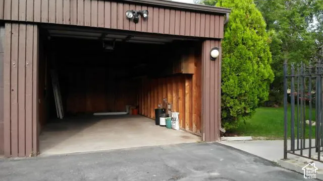 Spacious attached garage with concrete flooring and wood-paneled interior walls