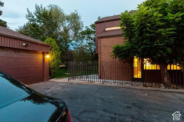 Exterior featuring brick and vertical wood-finish siding, an attached two-car garage, and a gated perimeter