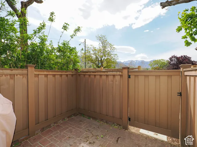 Enclosed patio space featuring brick paver flooring and a private access gate