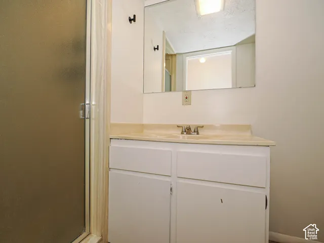 Bathroom vanity featuring a light-toned countertop with integrated sink, white cabinetry with two doors and two drawers, and a wall-mounted mirror