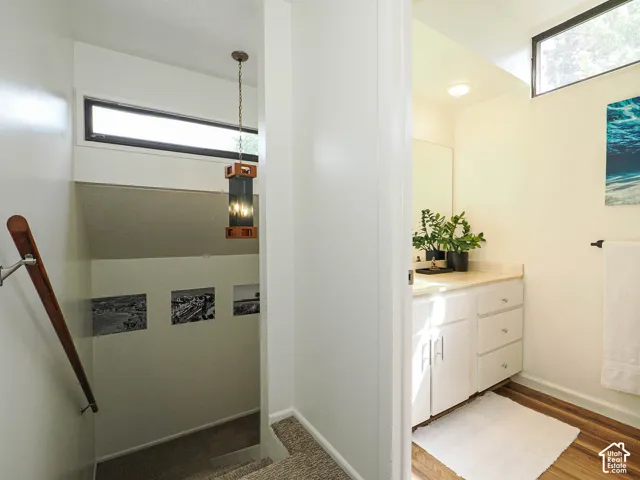 Bathroom vanity with white cabinetry, light-toned countertop, and wood-finish flooring