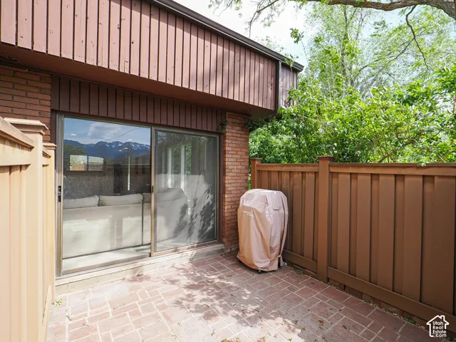 Private patio featuring brick pavers and a full-height wooden privacy fence