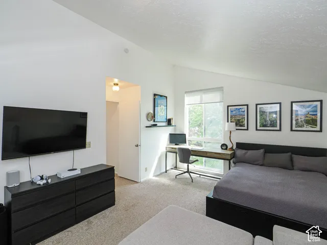 Carpeted room featuring a large window, white walls, and a sloped ceiling