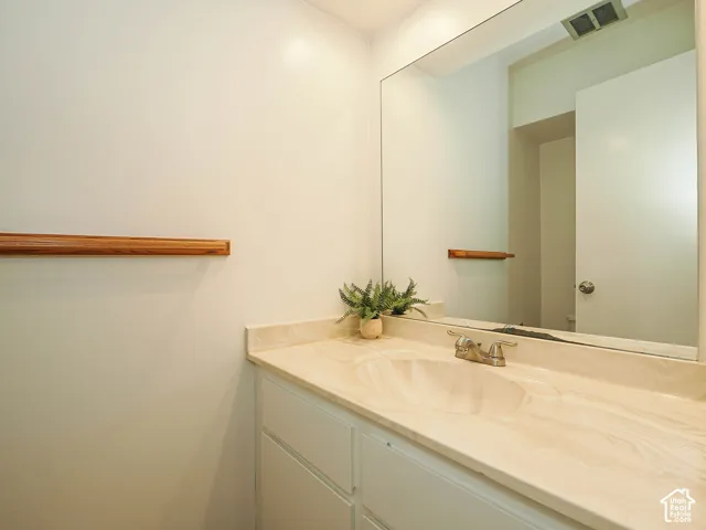 Bathroom vanity featuring a built-in sink and a light-toned countertop, complemented by a large mirror and a light wood-finish wall accent