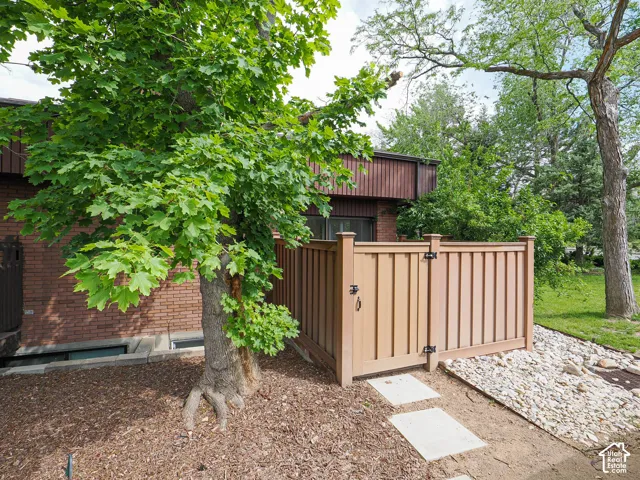 Private outdoor area featuring a tall privacy fence with a gate, concrete stepping stones, and a mulched garden bed