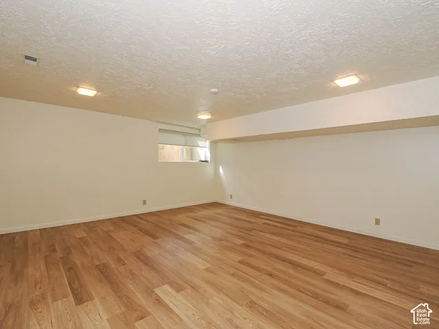 Spacious room featuring light wood-finish flooring, neutral wall tones, and recessed ceiling lighting