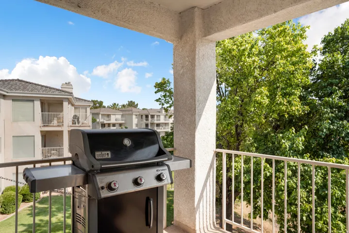 Private balcony with an exterior railing, offering green tree foliage and a distant building backdrop