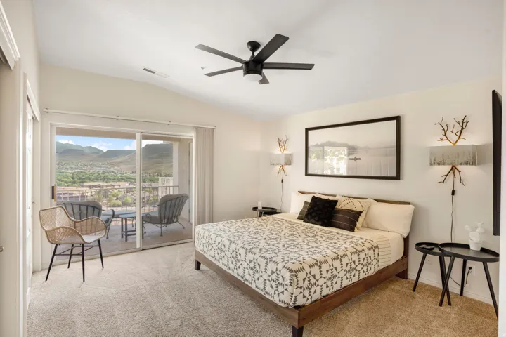 Room with light beige carpeting and a vaulted ceiling featuring a dark-toned ceiling fan